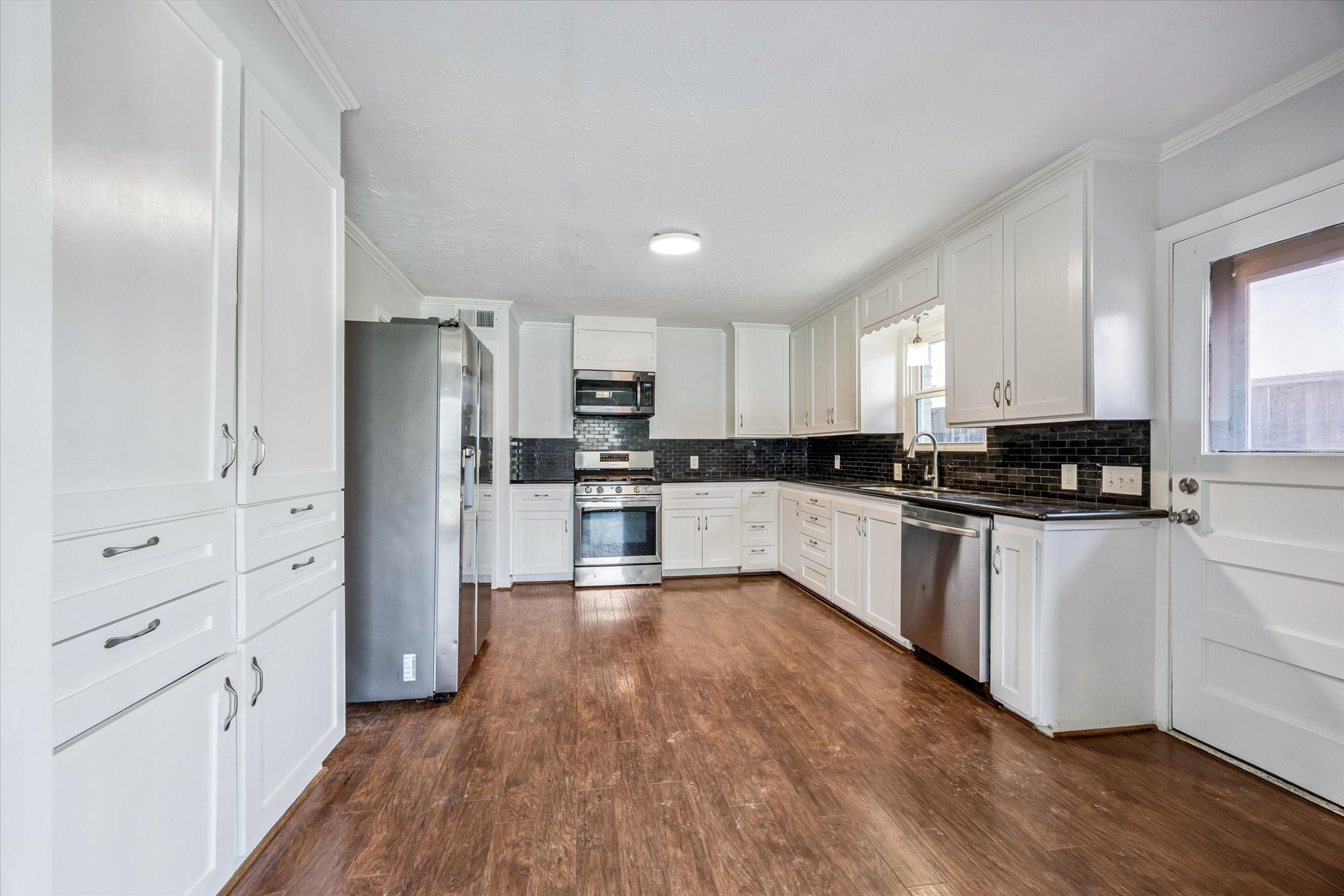 3607 Blue Bonnet Boulevard Houston, TX 77025 - Photo 3 of 14 a kitchen with white cabinets and stainless steel appliances
