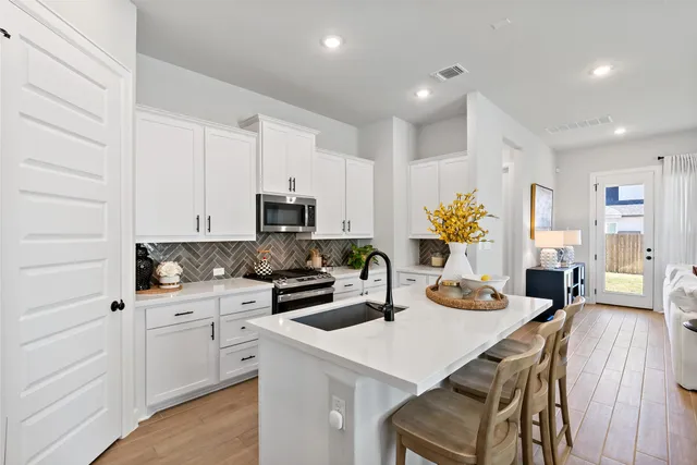 a kitchen with white cabinets and appliances