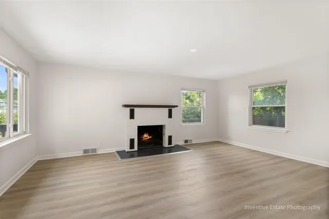 an empty room with windows and a fireplace