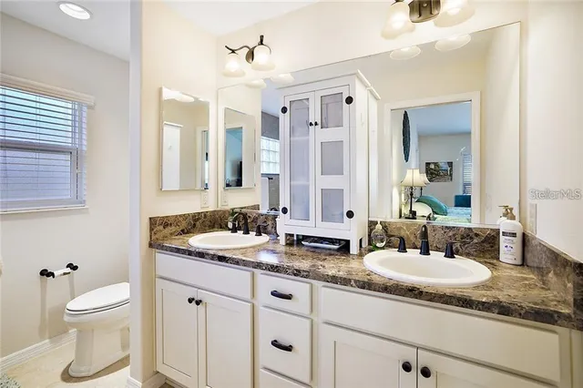 a bathroom with a granite countertop sink mirror and a toilet