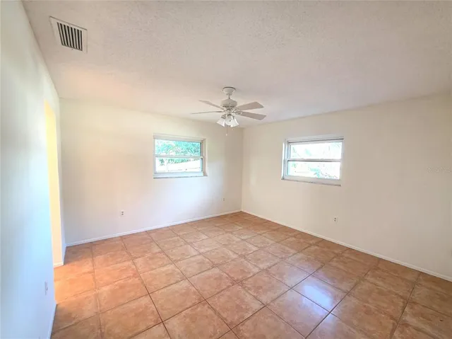 an empty room with windows and fan