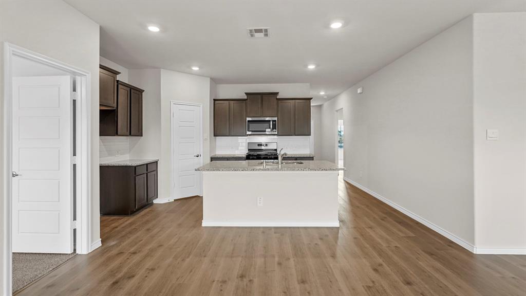 111 Lantern Road Caddo Mills, TX 75135 - Photo 11 of 40 a living room with stainless steel appliances kitchen island granite countertop wooden floors a stove and a refrigerator