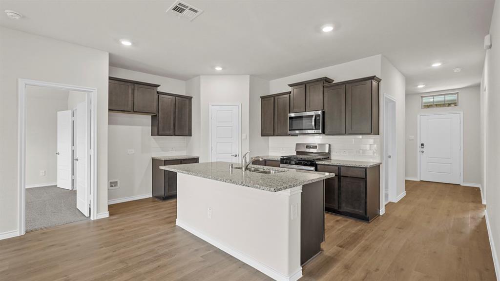 111 Lantern Road Caddo Mills, TX 75135 - Photo 10 of 40 a kitchen with stainless steel appliances granite countertop a stove top oven a sink dishwasher a refrigerator and a oven with wooden floor