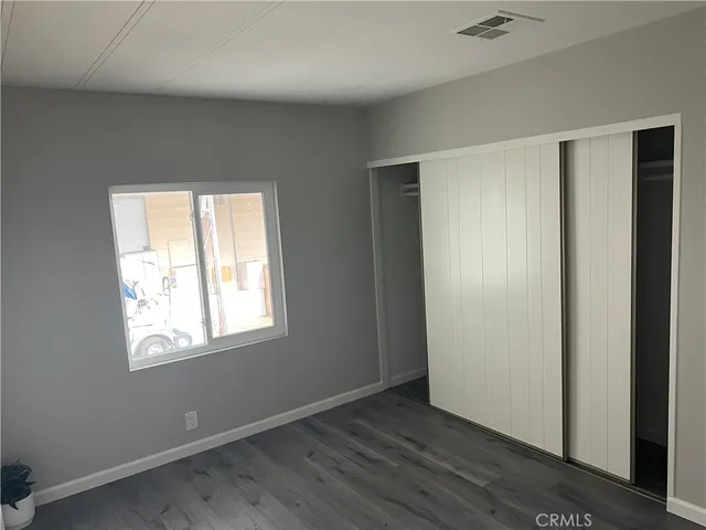 an empty room with wooden floor closet and windows