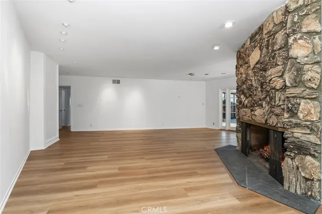 a view of empty room with wooden floor and fireplace