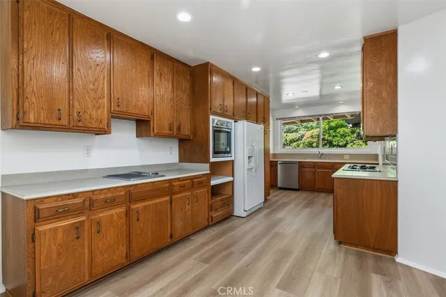 a kitchen with stainless steel appliances granite countertop wooden cabinets a refrigerator and a sink