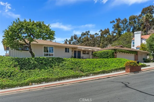 a front view of a house with a yard and potted plants