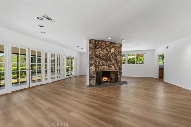 a view of an empty room with wooden floor and a fireplace