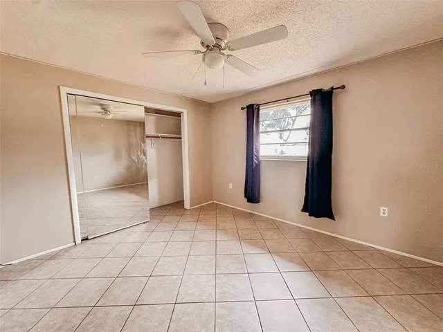 a view of an empty room with window and chandelier fan