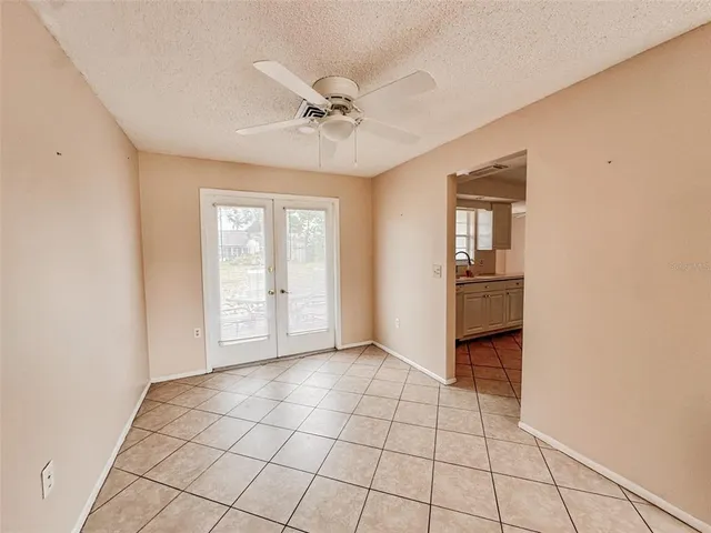 a view of an empty room with window and chandelier fan