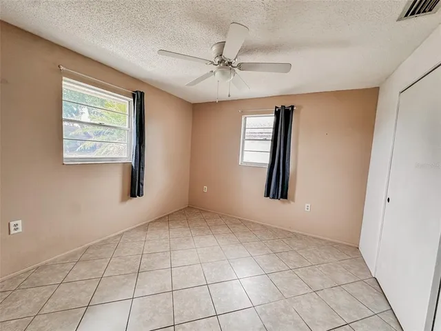 an empty room with windows and fan