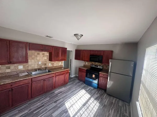 a kitchen with stainless steel appliances granite countertop a refrigerator sink and wooden cabinets