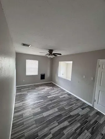a view of empty room with window and ceiling fan