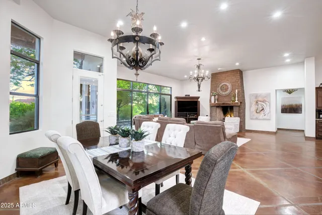 a view of a dining room with furniture a chandelier and large windows