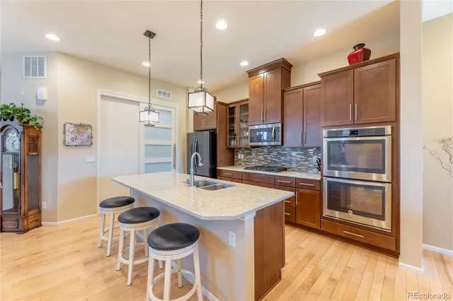 a kitchen with stainless steel appliances kitchen island granite countertop a table chairs and a refrigerator