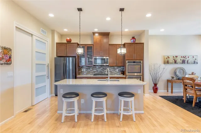 a kitchen with stainless steel appliances kitchen island granite countertop a dining table chairs and white cabinets