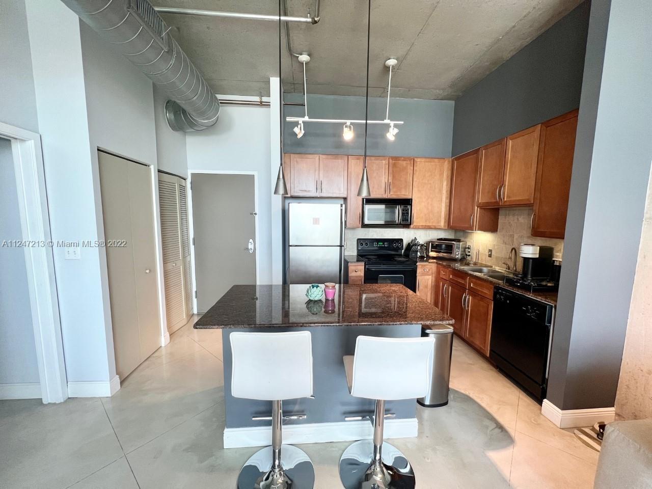 2001 Biscayne Boulevard, Unit 2414 Miami, FL 33137 - Photo 2 of 8 a kitchen with stainless steel appliances kitchen island granite countertop a refrigerator and microwave