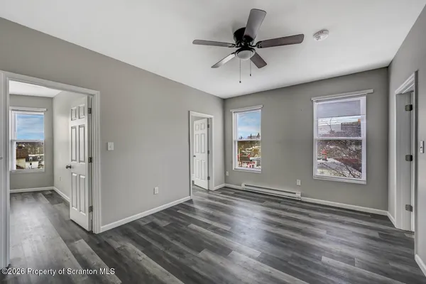a view of an empty room with window and wooden floor