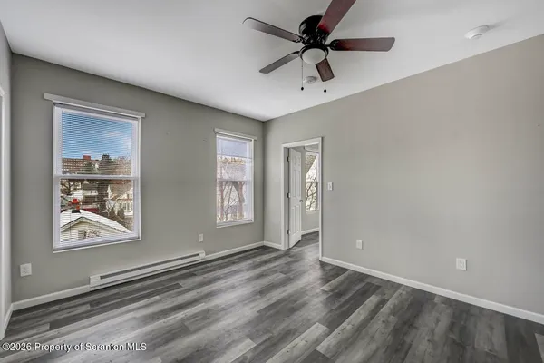 a view of an empty room with a window and wooden floor