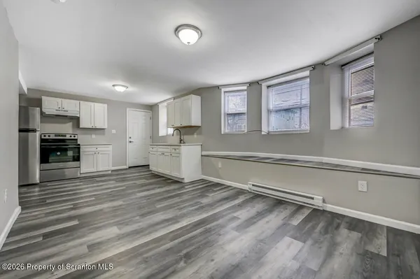 a large white kitchen with a stove a sink dishwasher and a refrigerator with wooden floor