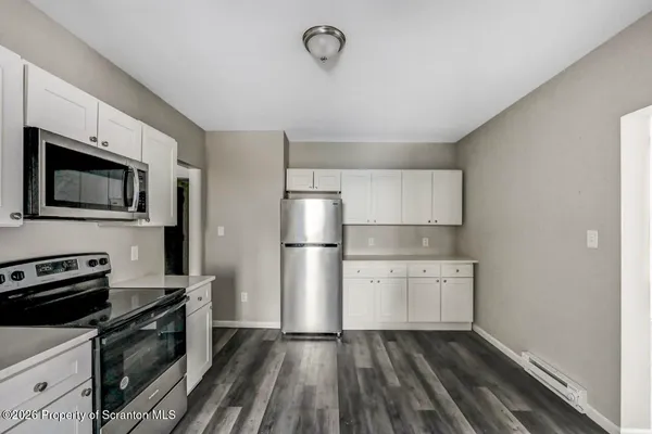 a kitchen with a refrigerator a stove and wooden floor