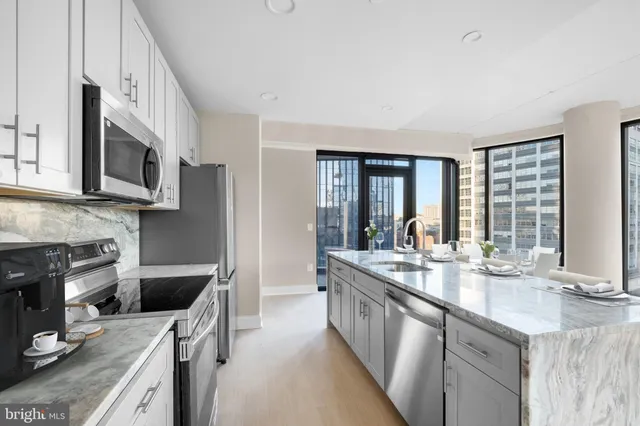 a kitchen with stainless steel appliances a kitchen island hardwood floor sink stove dining table and chairs