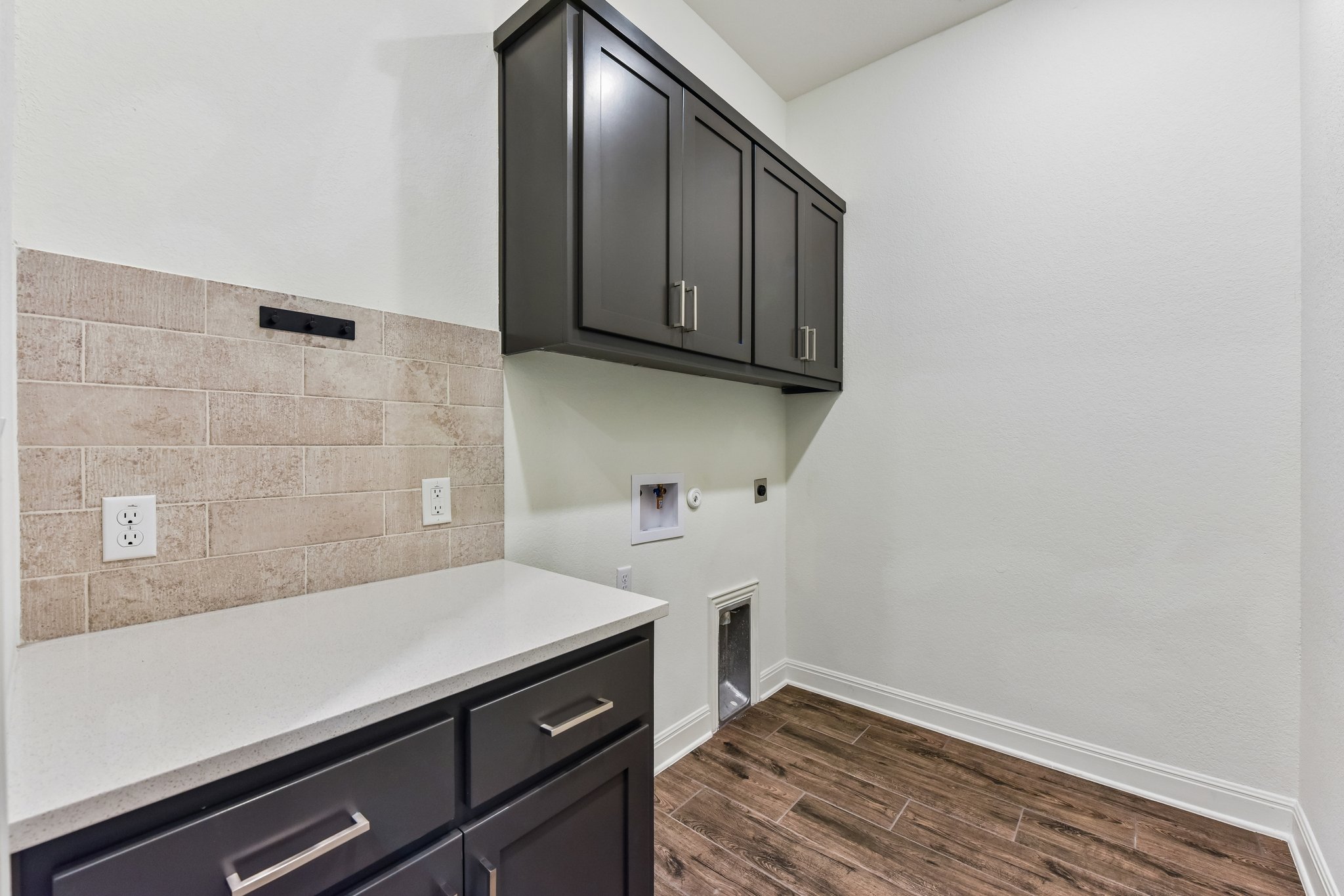 19113 Freeman Circle Austin, TX 78738 - Photo 23 of 37 Functional laundry space featuring ample cabinetry and wood-look tile flooring.
