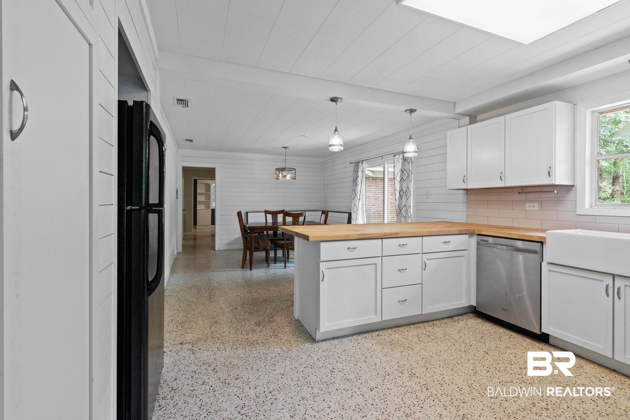 384 Old Bratt Road Atmore, AL 36502 - Photo 14 of 64 Bright kitchen featuring white cabinetry, light wood-finish countertops, stainless steel dishwasher, and a white farmhouse sink