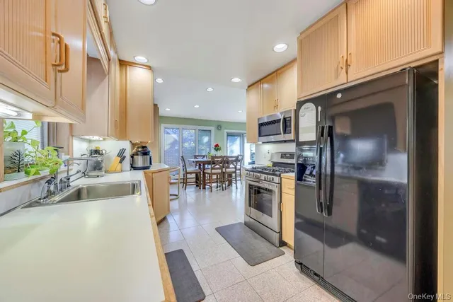 a kitchen with stainless steel appliances granite countertop a refrigerator a sink a stove and a oven with wooden floor