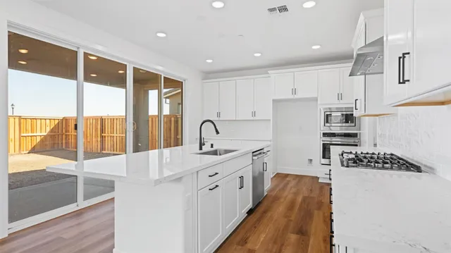 a kitchen with stainless steel appliances granite countertop a sink stove and refrigerator