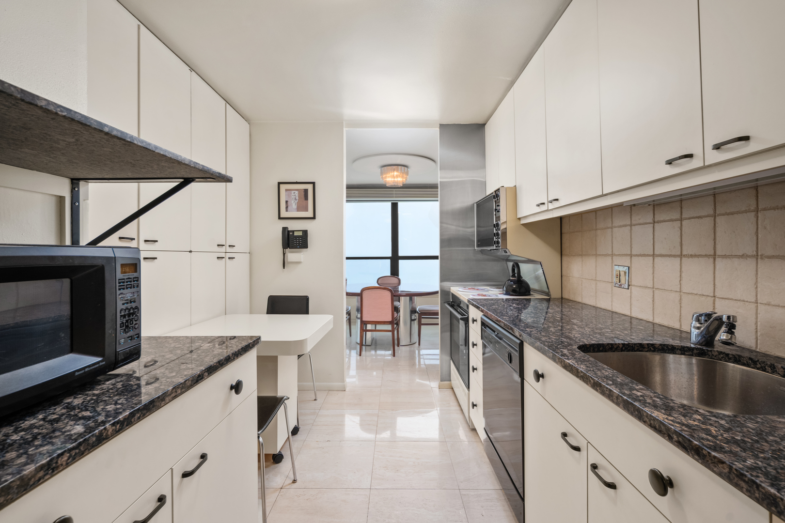 1030 North State Street, Unit 51EF Chicago, IL 60610 - Photo 7 of 20 a kitchen with stainless steel appliances kitchen island granite countertop a sink and cabinets