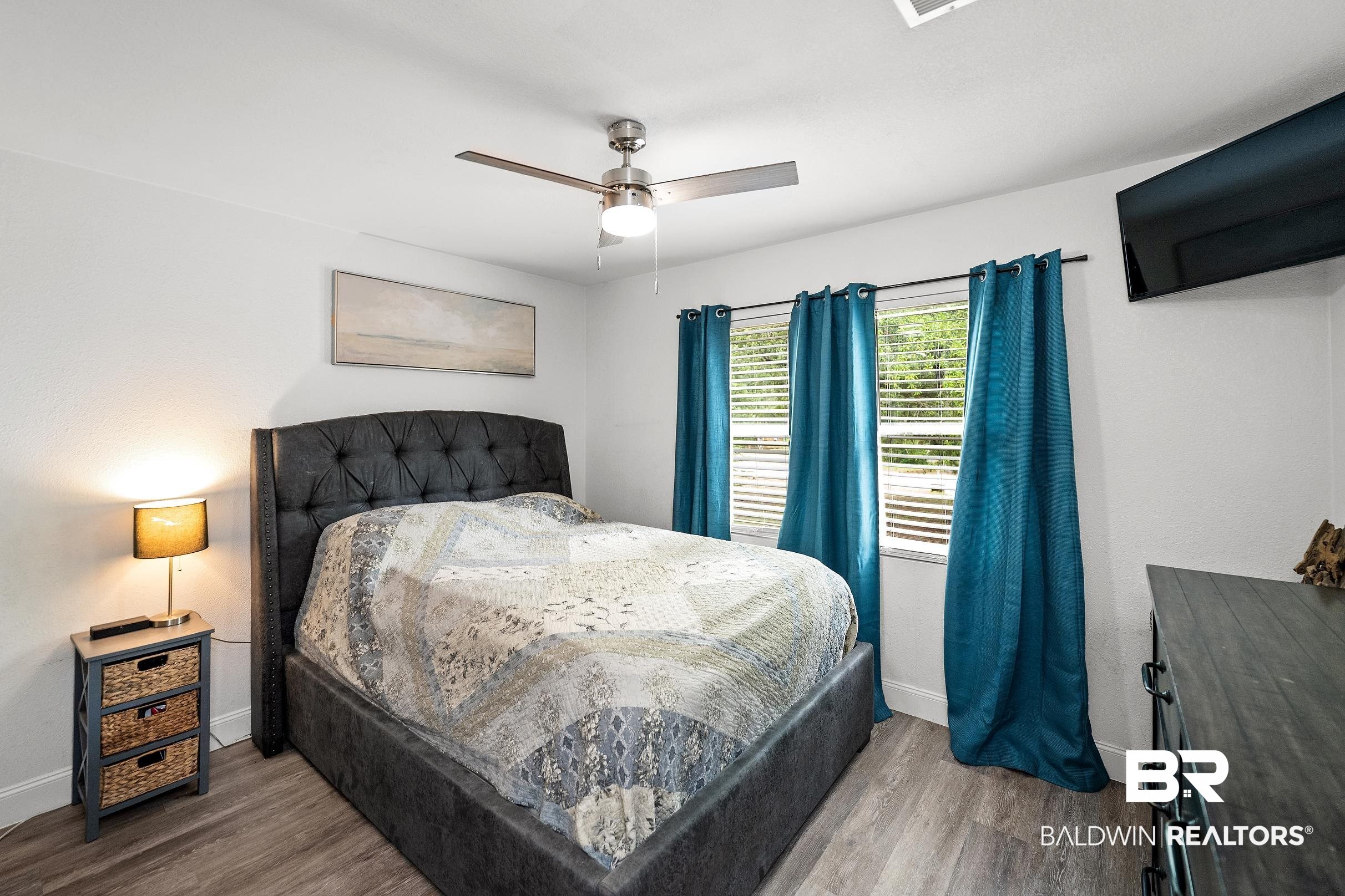 33129 Antietam Road Lillian, AL 36549 - Photo 17 of 31 Bright room featuring two windows with blinds, a ceiling fan, and wood-finish flooring