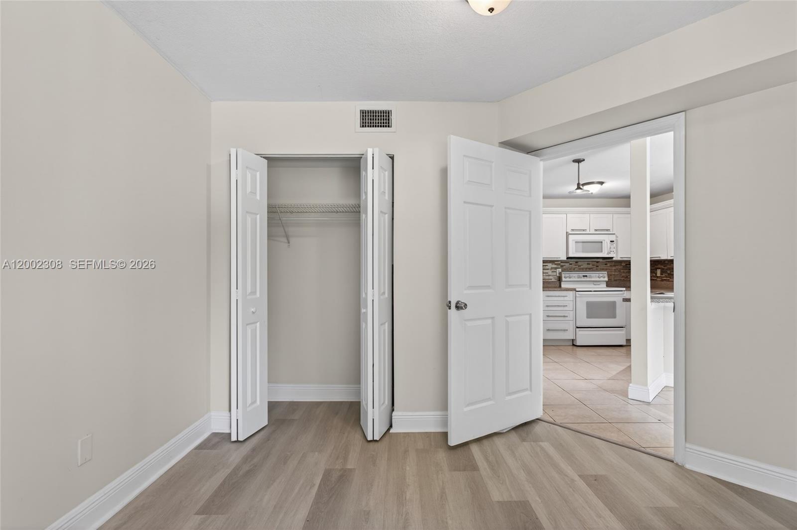 4025 West McNab Road, Unit E109 Pompano Beach, FL 33069 - Photo 11 of 27 a view of a hallway with wooden floor and a kitchen
