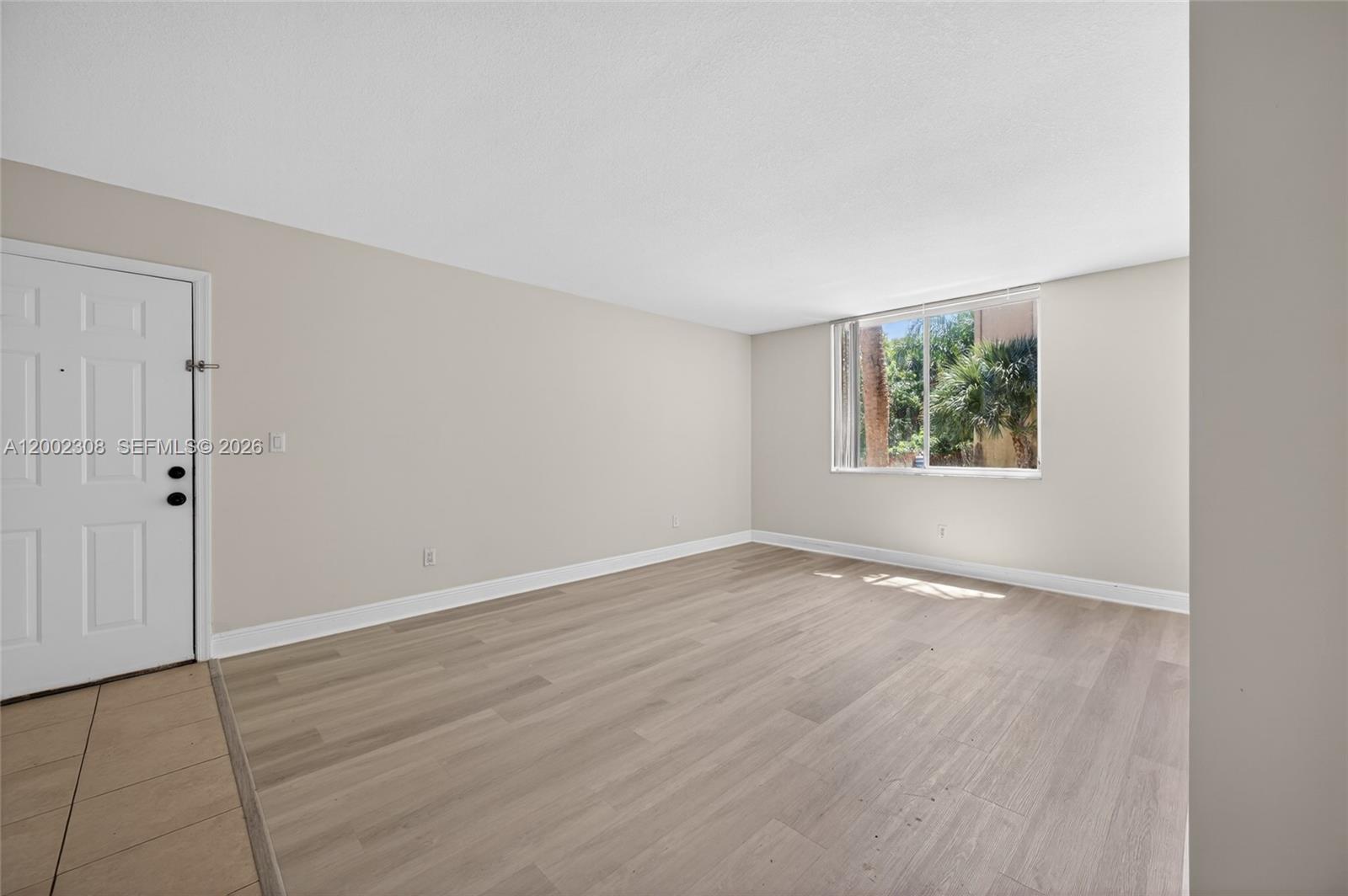 4025 West McNab Road, Unit E109 Pompano Beach, FL 33069 - Photo 3 of 27 an empty room with wooden floor and window