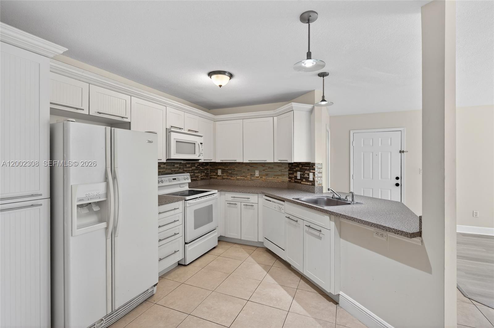 4025 West McNab Road, Unit E109 Pompano Beach, FL 33069 - Photo 4 of 27 a kitchen with white cabinets and white appliances