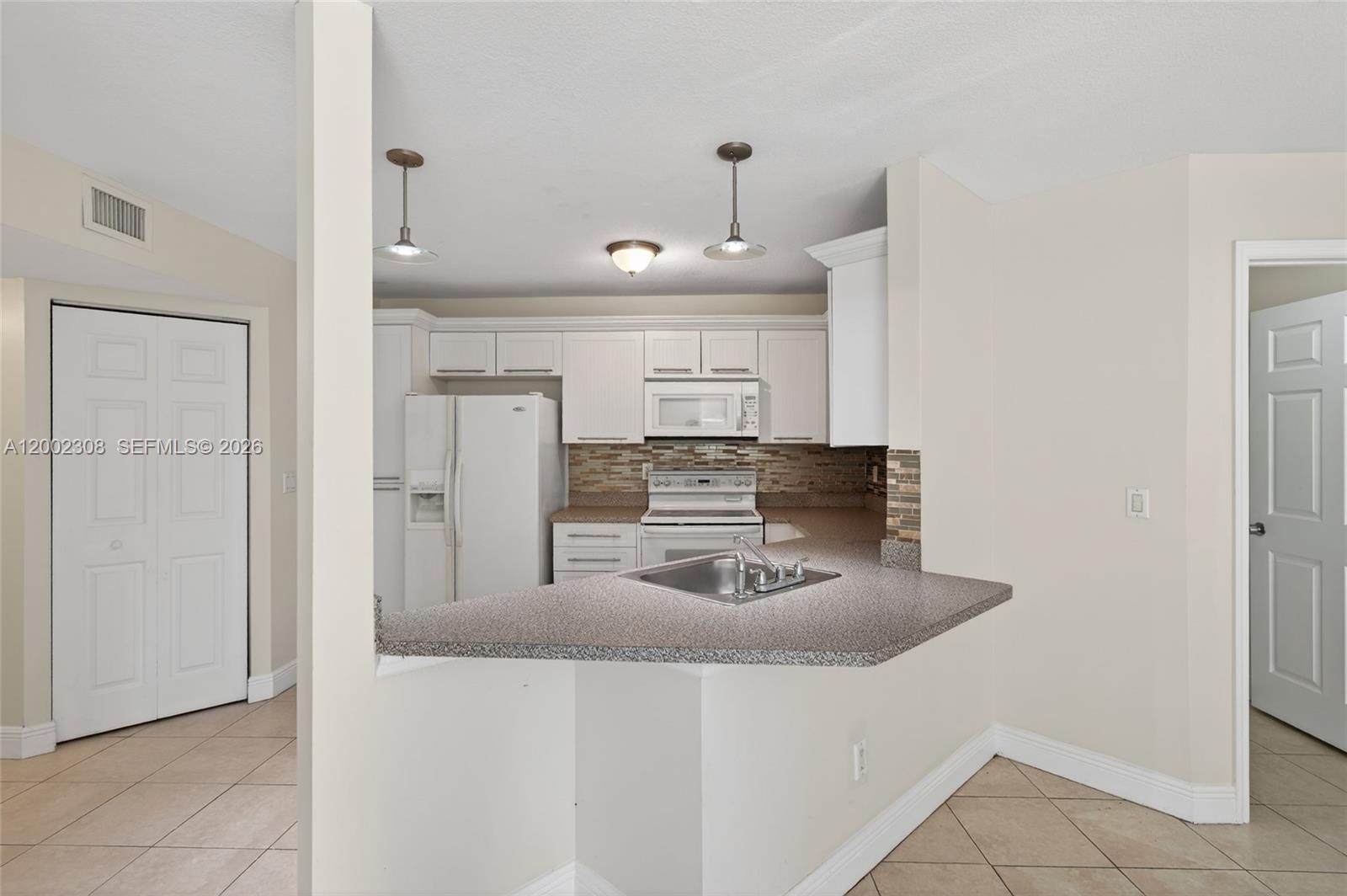 4025 West McNab Road, Unit E109 Pompano Beach, FL 33069 - Photo 5 of 27 a kitchen with kitchen island a counter top space a sink and refrigerator