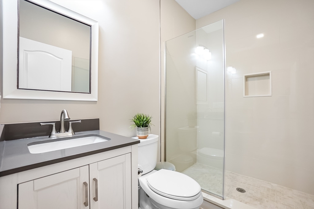 57 Walnut Street Newton, MA 02460 - Photo 16 of 42 a bathroom with a toilet a sink a glass door a shower a mirror and vanity