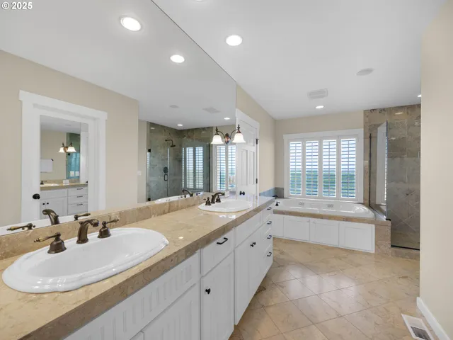 a bathroom with a sink tub double vanity and mirror