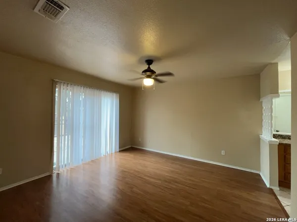 an empty room with wooden floor fan and windows