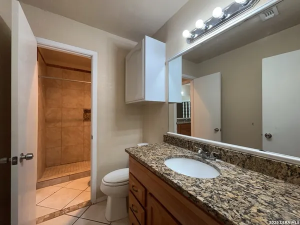 a bathroom with a granite countertop sink toilet and shower