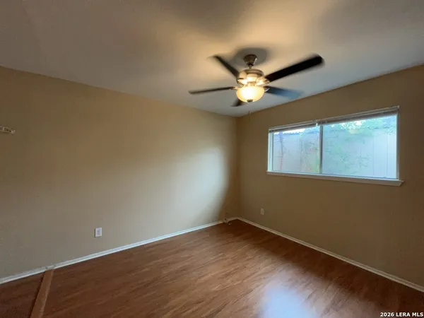 a view of an empty room with a window and wooden floor