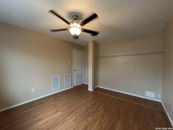 an empty room with wooden floor fan and windows