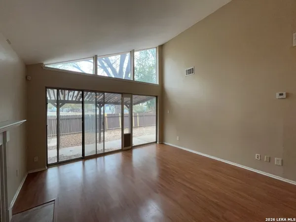 an empty room with wooden floor and windows