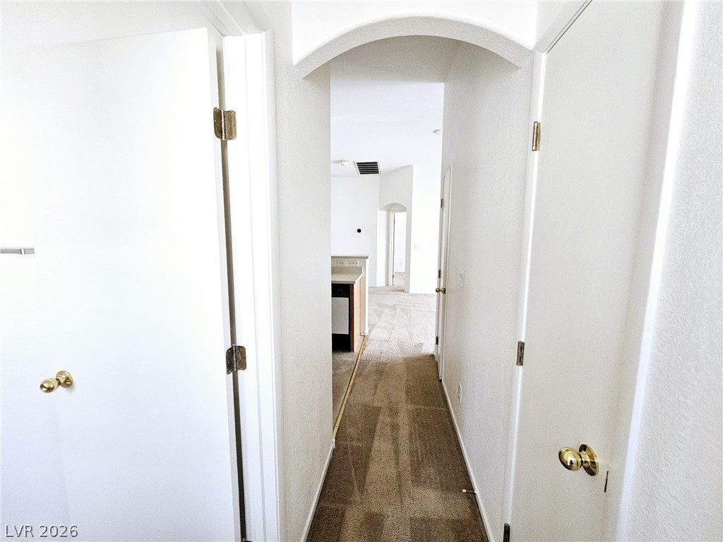 1663 Lefty Garcia Way Henderson, NV 89002 - Photo 13 of 31 A well-lit interior hallway features an arched doorway and neutral carpet flooring.