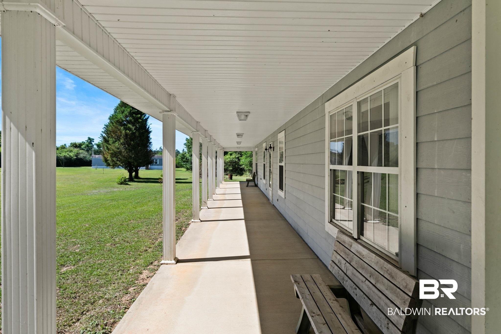 20219 Greek Cemetery Road Robertsdale, AL 36567 - Photo 12 of 41 Expansive covered porch featuring white support columns and a concrete walkway