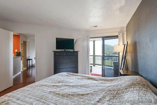 a bedroom with a bed and a flat tv screen next to a window