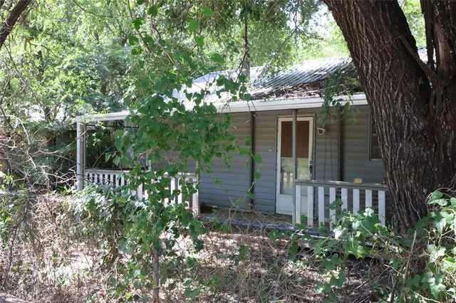 a view of a house with a small yard plants and large tree