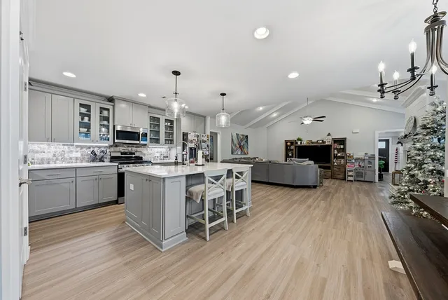 a kitchen with stainless steel appliances kitchen island granite countertop a table chairs sink and cabinets