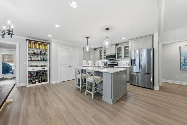 a kitchen with stainless steel appliances a dining table chairs and wooden floor
