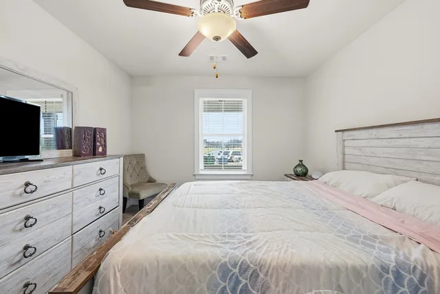 a bedroom with a bed and a flat tv screen on dresser